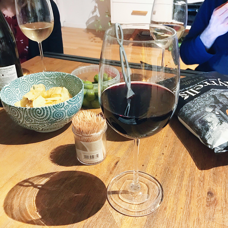 Drink Pure Wine wine wand immersed in a glass of red wine, surrounded by snacks.